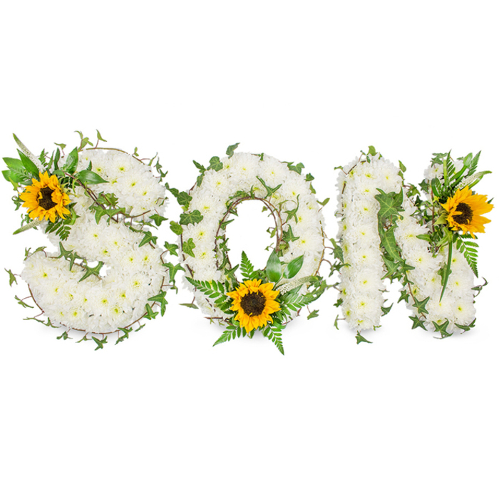 A highly detailed, three-dimensional funeral tribute spells SON in solid capital letters, each letter densely surfaced with hundreds of delicate white chrysanthemum heads that form a continuous, cushion-like texture. The chrysanthemums are compacted closely enough to read from a distance as clean, luminous white blocks, yet close inspection reveals individual petals and subtle shading where blooms overlap. Dark green ivy vines with characteristic lobed leaves are threaded thoughtfully through the letters, trailing along edges and wrapping gently around curves to add depth and a natural, evergreen rhythm. Intermingled sprigs of fern and lighter green foliage lift the overall profile and introduce fine, feathery texture against the chrysanthemum mass. Three large sunflowers punctuate the composition: one placed on the upper-left curve of the S, another set low in the round of the O among verdant fern fronds, and a third positioned at the upper-right of the N. Each sunflower presents broad golden-yellow rays that contrast dramatically with the white chrysanthemums, and their dark brown, textured centres provide a focal warmth that draws the eye. The arrangement is lit with soft, even illumination and photographed on a stark white backdrop to emphasize form, tone, and botanical detail. As a bespoke memorial piece suitable for services around Forest Gate-near Westfield Stratford City, Wanstead Flats, or the quiet corners by Woodgrange Park-this tribute balances classic bereavement symbolism with a hopeful brightness, making it a considered choice for families wanting to honour a son with dignity and a touch of light.