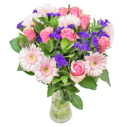Arranged with the thoughtful expertise that defines Forest Gate Flowers, this bouquet is a luminous celebration of pink gerberas and classic roses-each petal unfolding gracefully, like the soft clouds above Wanstead Park after a spring rain. Light blush tones blend harmoniously, conjuring the gentle serenity of local gardens and tree-lined avenues. The joyful presence of deep purple statice punctuates the arrangement, adding cheerful contrast and a hint of whimsy. I take special care with the foliage, selecting only the freshest, dew-cooled greens to create a full and inviting backdrop that frames the blooms above. Set against a pristine glass vase, every stem and swirl is visible, a testament to the beauty and transparency of nature. The overall effect is airy and optimistic, perfect for a get-well wish, a 'thinking of you' delivery along Romford Road, or as a stylish highlight in a Forest Gate living room. Each element has been thoughtfully composed to evoke joy, renewal, and the gentle craftsmanship for which local floristry is known. In this bouquet, colour and form unite to offer both comfort and delight for any occasion.